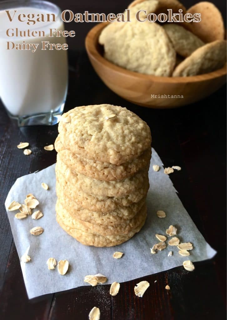 oatmeal cookies are stacked and a glass of milk is on the table