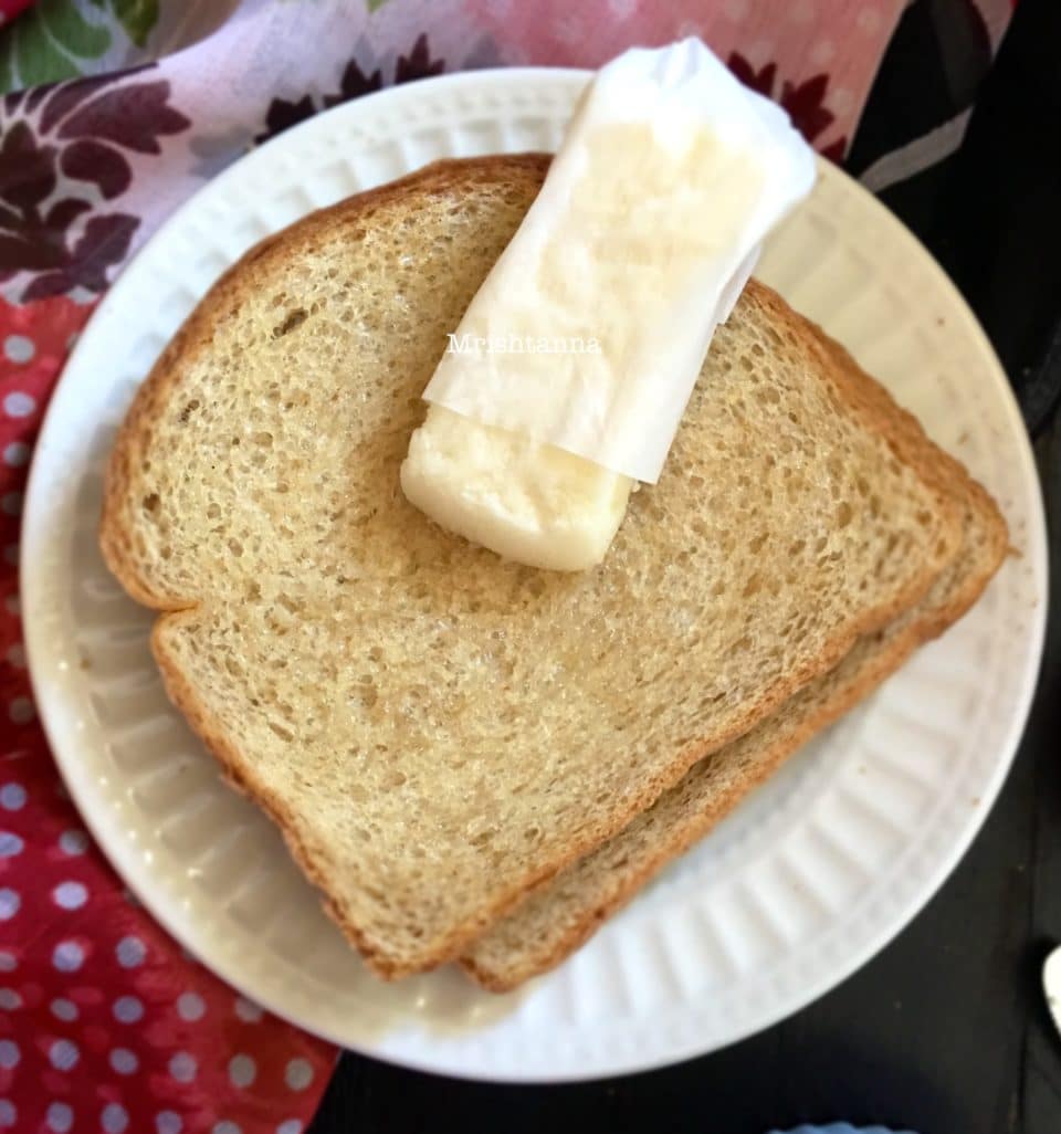 A sandwich cut in half on a plate, with Vegan Butter