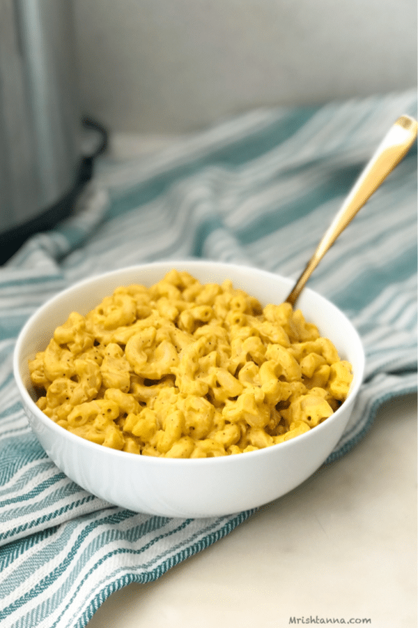 A bowl of mac and cheese with a golden spoon inserted