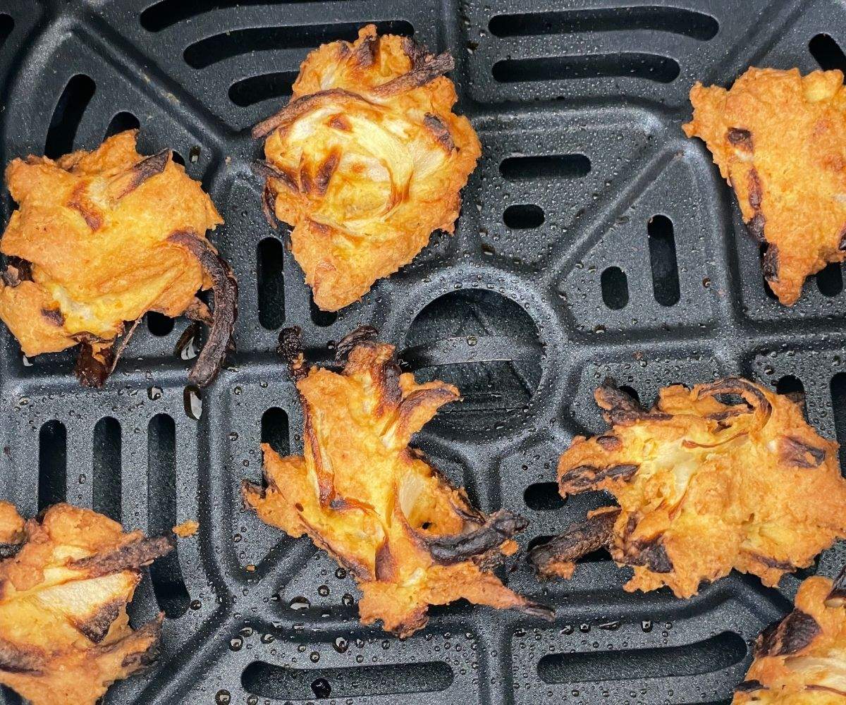 Air fryer basket is with crispy onion pakoda.