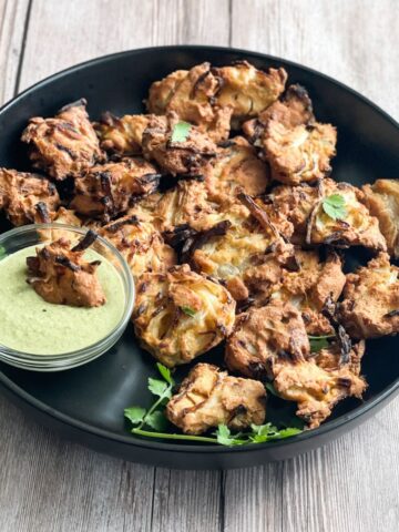 A plate is with air fried onion pakoras.