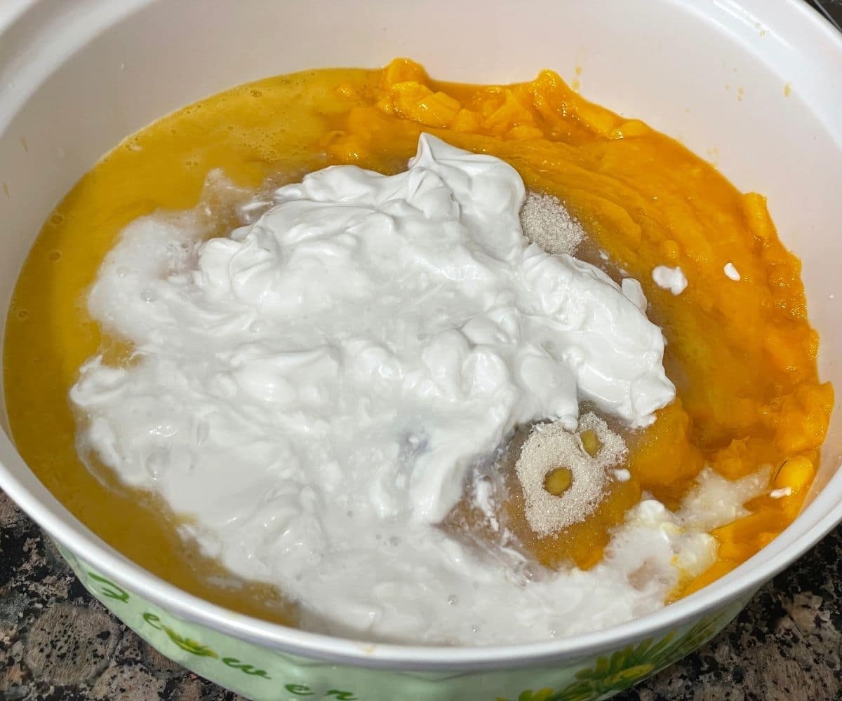 A bowl is with mango pulp, coconut milk and other ingredinets.