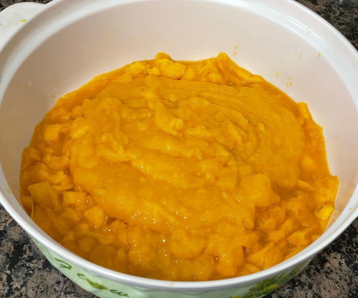 A bowl is with mango pulp and chopped mangoes.