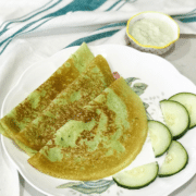 A plate of cucumber dosas on the table along with chutney by the side