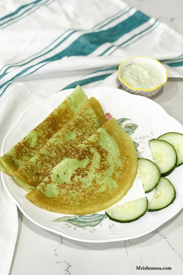 A plate of cucumber dosas on the table along with chutney by the side