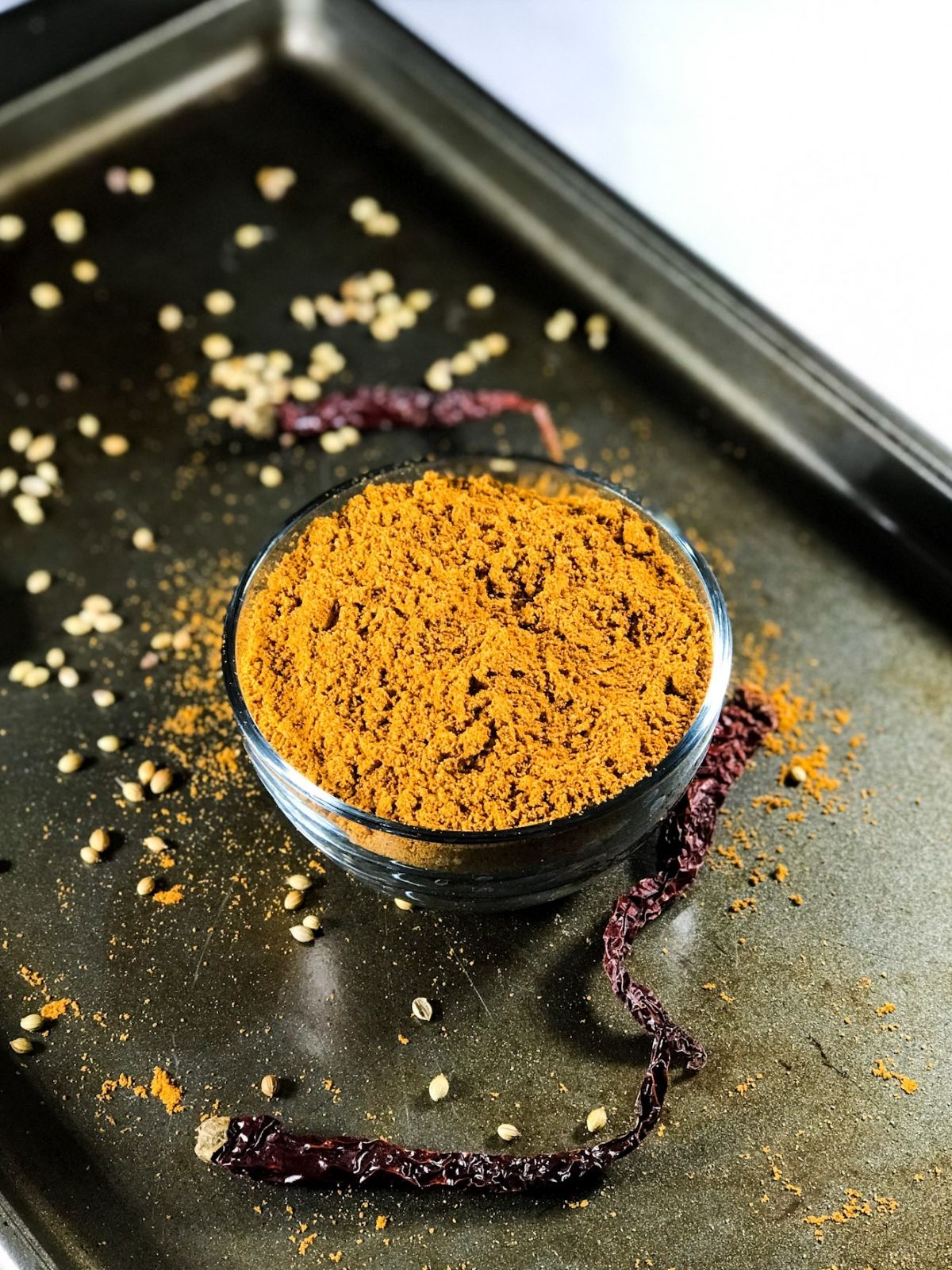 A bowl of sambar powder is on the aluminium tray