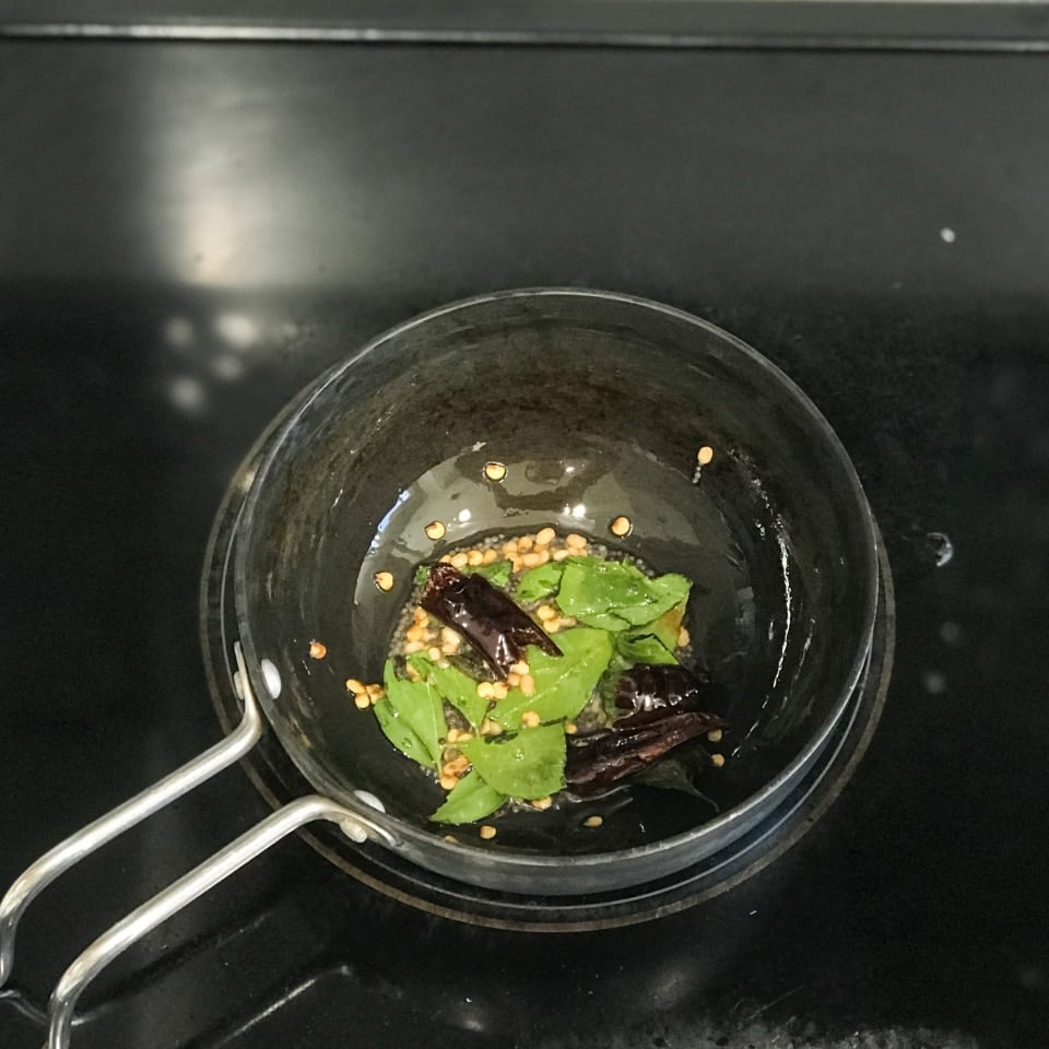 A small pan with oil and spices over the stove top