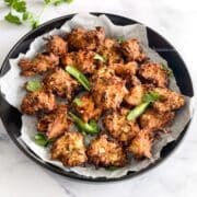 Air fryerCabbage pakoras are plated with parchment paper in it.