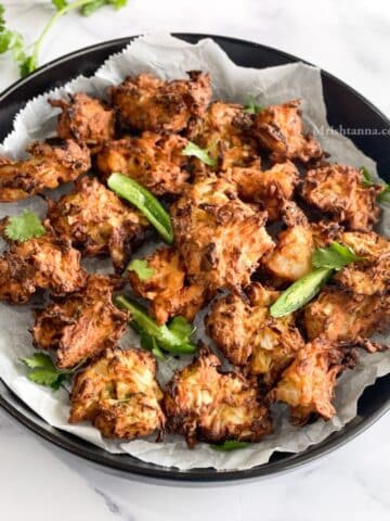 Air fryerCabbage pakoras are plated with parchment paper in it.