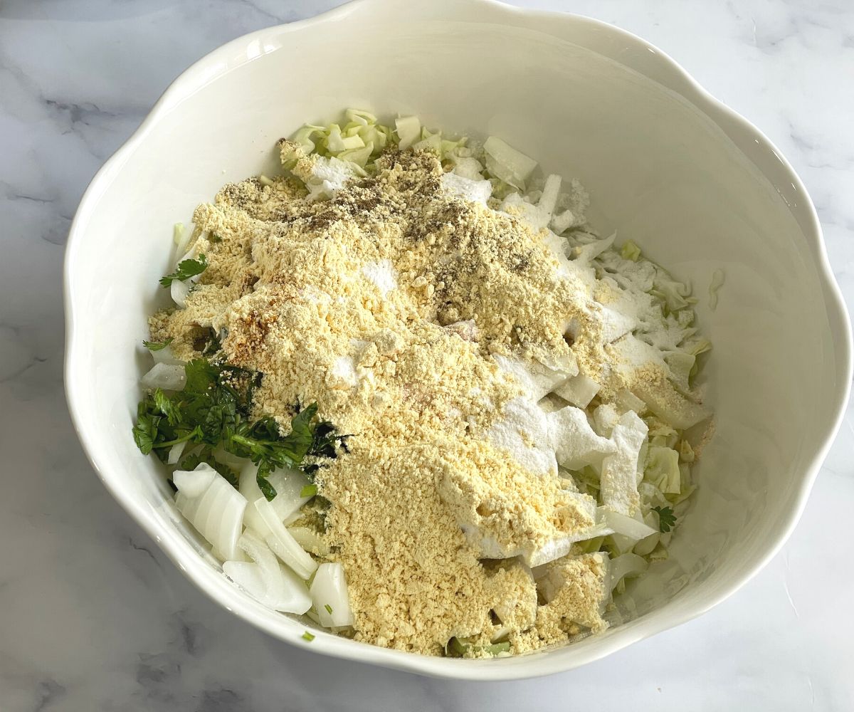 A bowl is with spice, flours and cabbage for pakora.