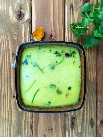 A bowl of moong dal rasam and topped with cilantro
