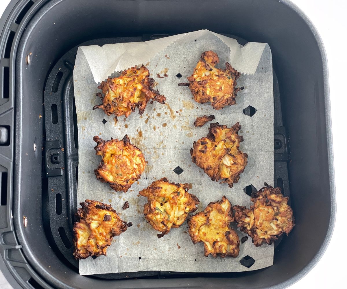 Air fryer basket is with fried cabbage pakoras.