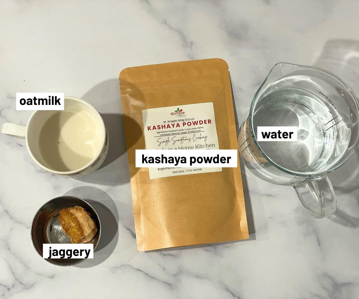 Ingredients for making kashayam: kashaya powder, water, oat milk, and jaggery arranged on a marble surface.