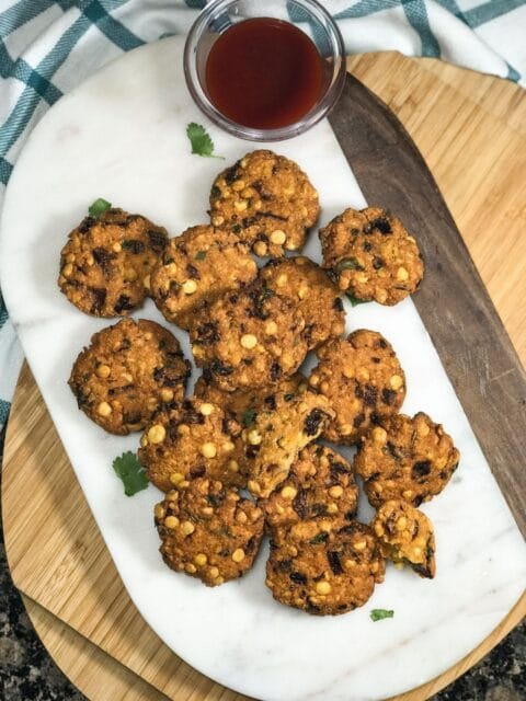 Masala vadas are placed on the white serving tray along with chutney