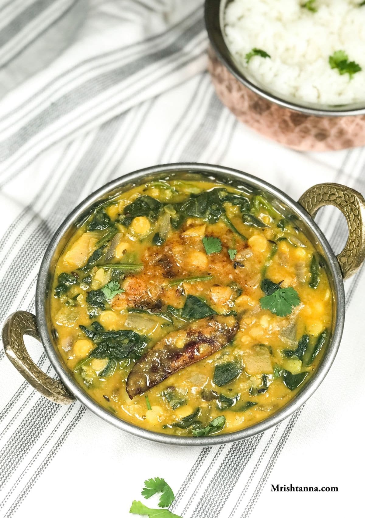 A bowl with spinach dal and garnished with red chili and cilantro