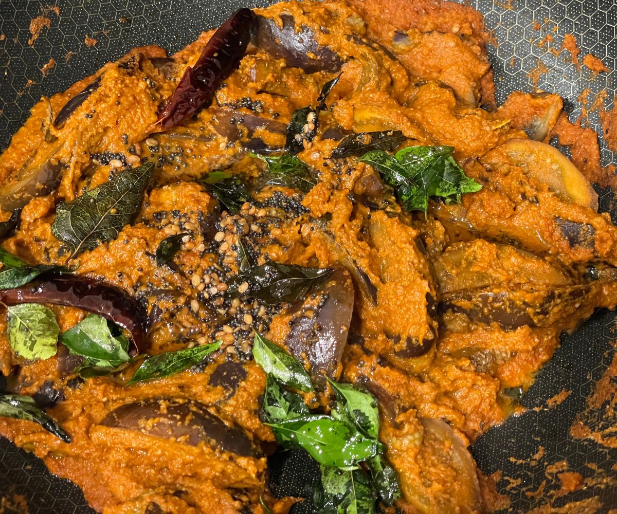 A pan has south Indian eggplant curry and topped with tempering.