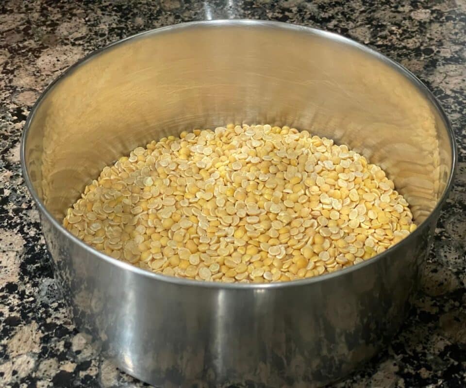 A pot is with dried yellow lentils on the counter tops.