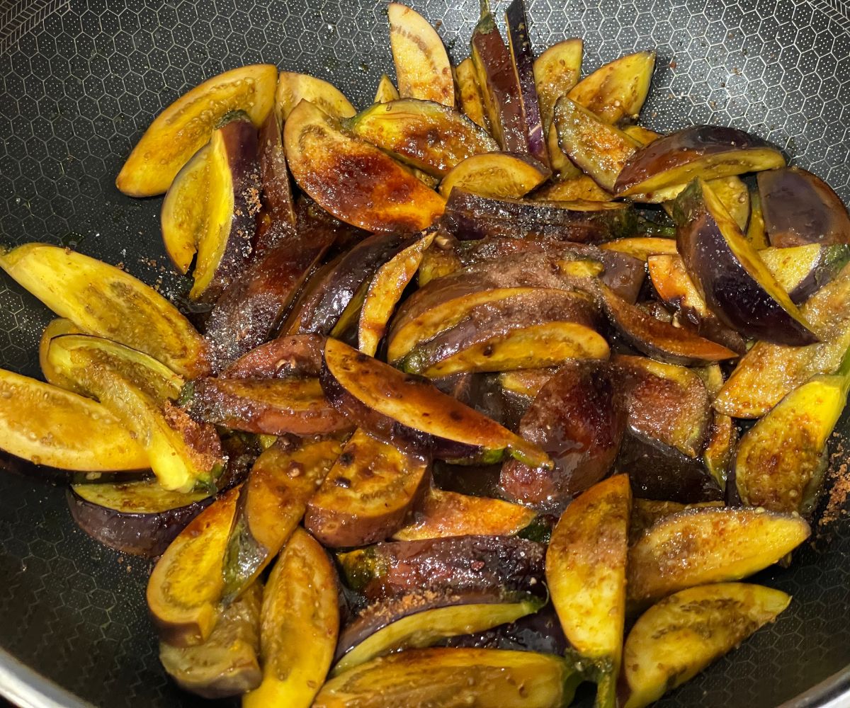 A pan has sauteed baby eggplants and spices.
