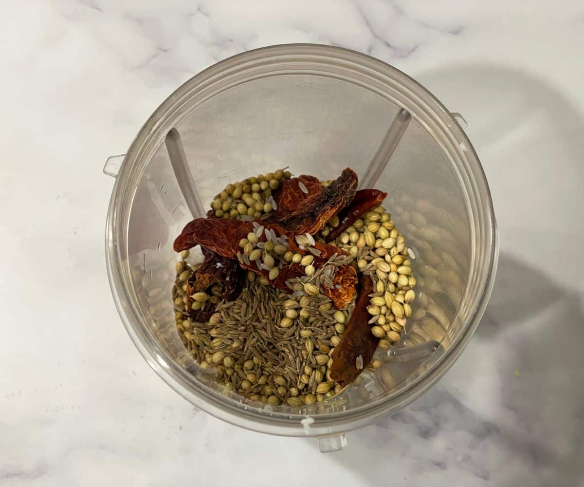 A blender has all the dry ingredients for brinjal masala curry.