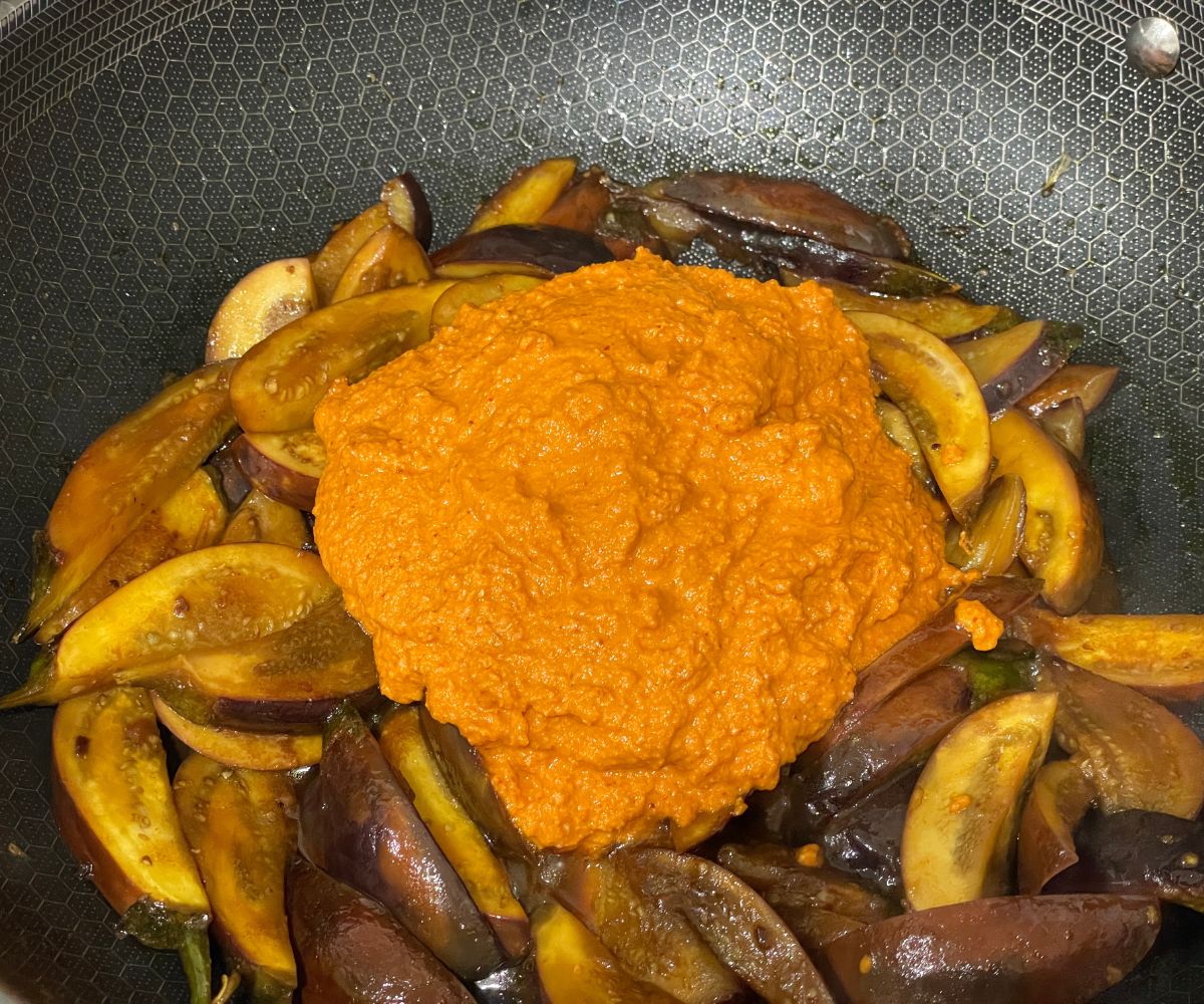 A pan has brinjal masala curry over the heat.