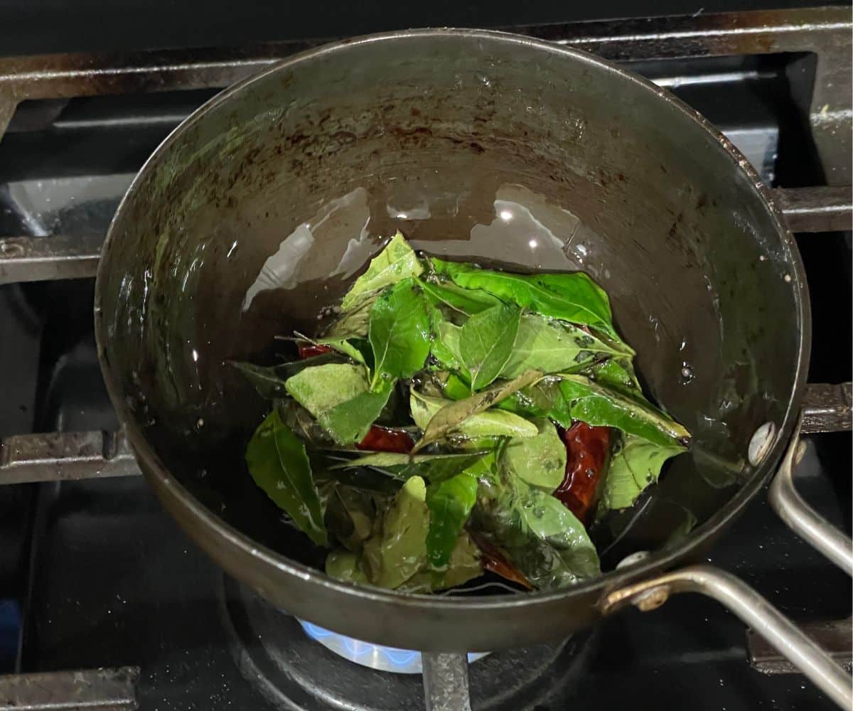 A pan has tempering ingredients over the heat.