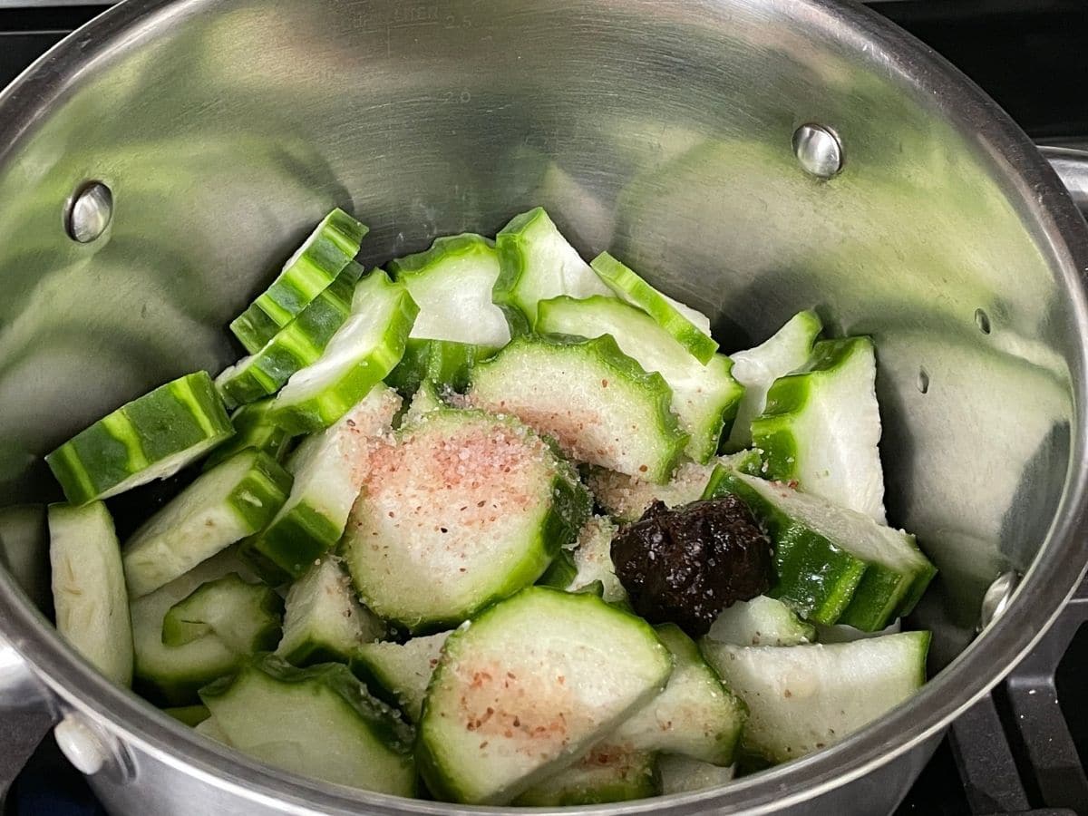 A pot is with ridge gourd, tamarind and water over the heat.