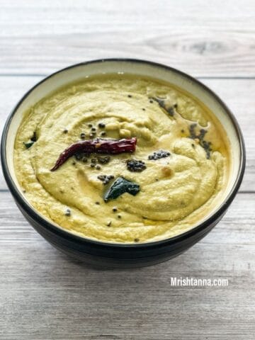 A bowl is filled with ridge gourd chutney and topped with tempering.