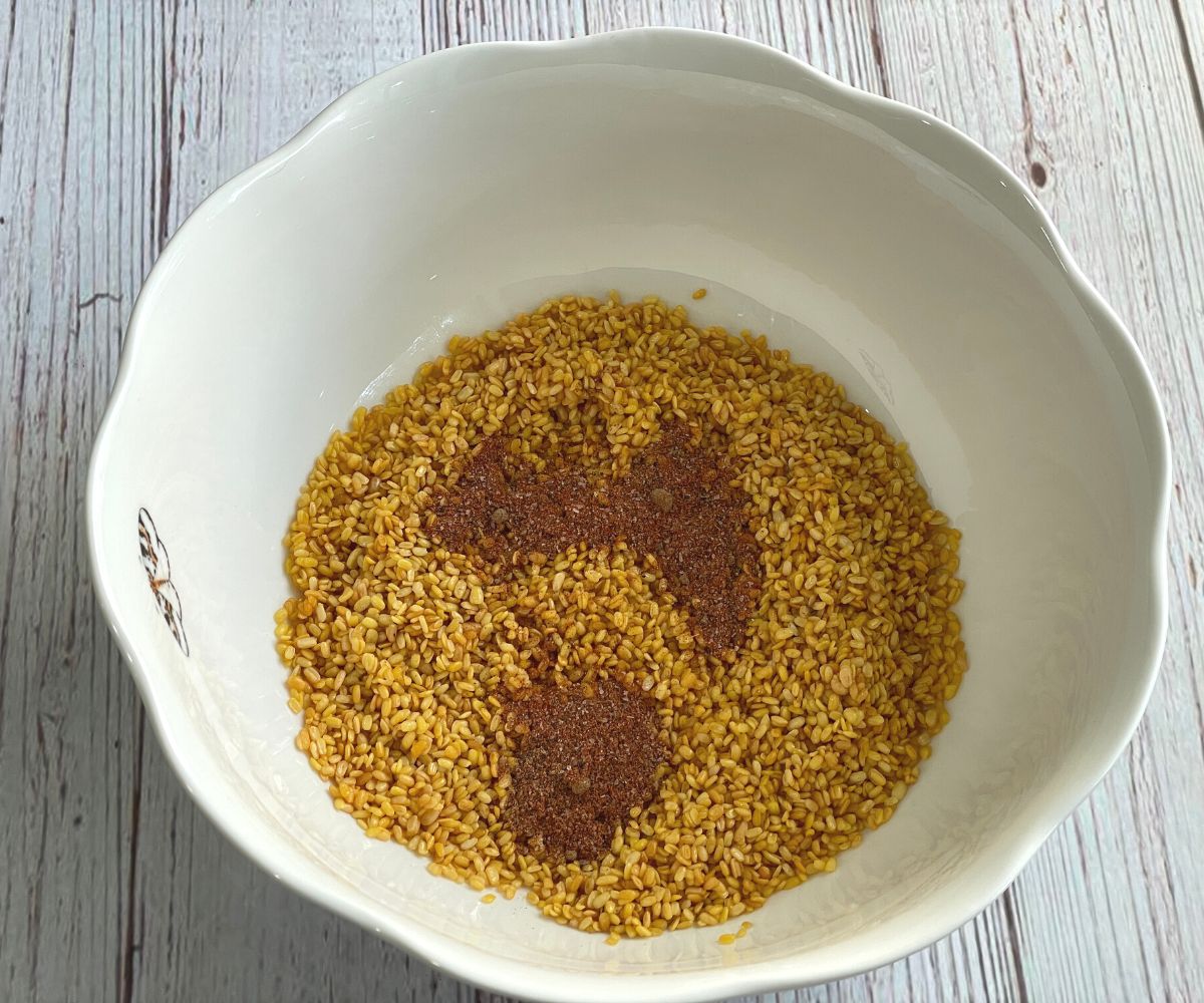 A bowl is with roasted moong dal and spices.