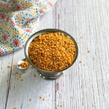 A steel bowl is with an air fryer roasted moong dal.