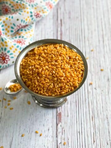 A steel bowl is with an air fryer roasted moong dal.