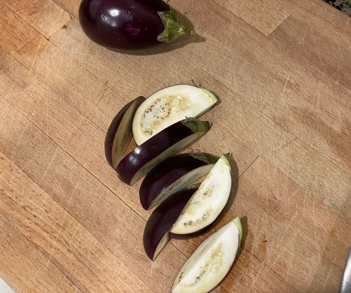 Sliced baby eggplants are on the chopping board.