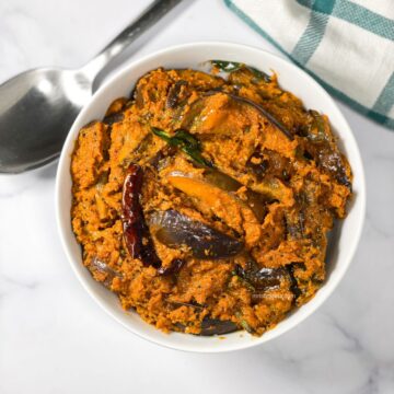 A bowl of brinjal curry is on the surface.