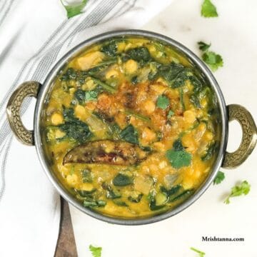 Spinach dal is in the copper bowl and tempering on the top