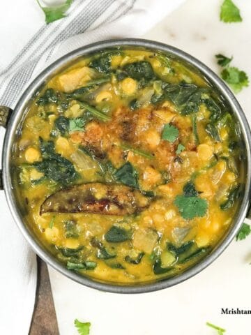 Spinach dal is in the copper bowl and tempering on the top