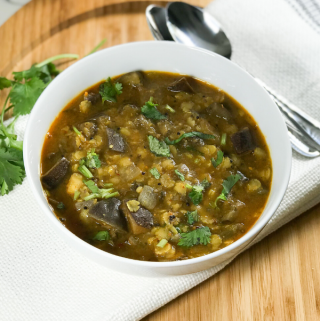 A bowl of brinjal sambar is on the table.