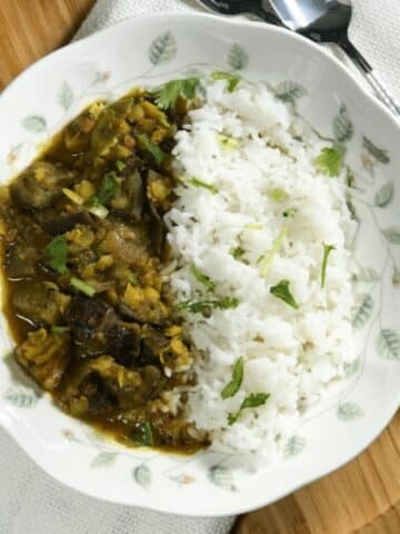A plate is with white rice and brinjal sambar.