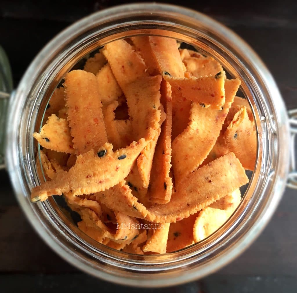 A plastic container filled with ribbon pakoda