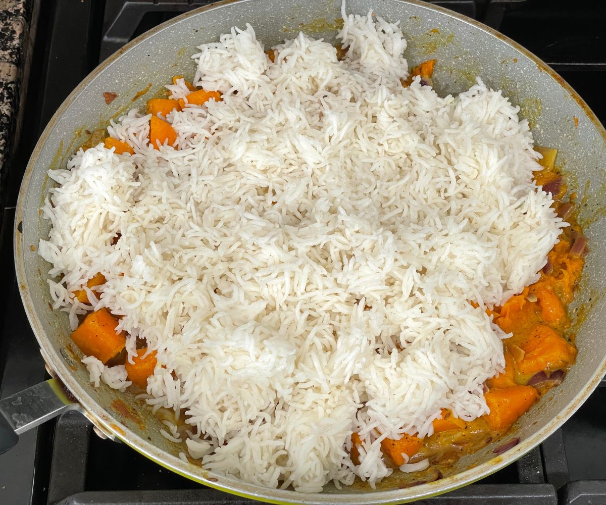 A pan is with pumpkin mixture and basmati rice over the heat.