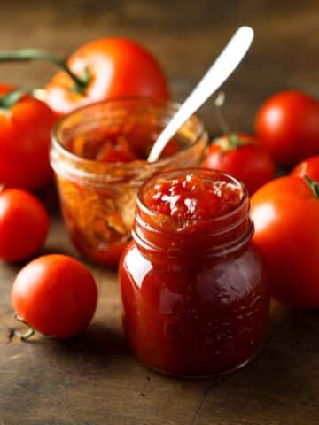 A glass jar is filled with homemade tomato jam.