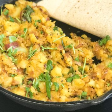 a cast iron skillet is filled with spicy potato curry.