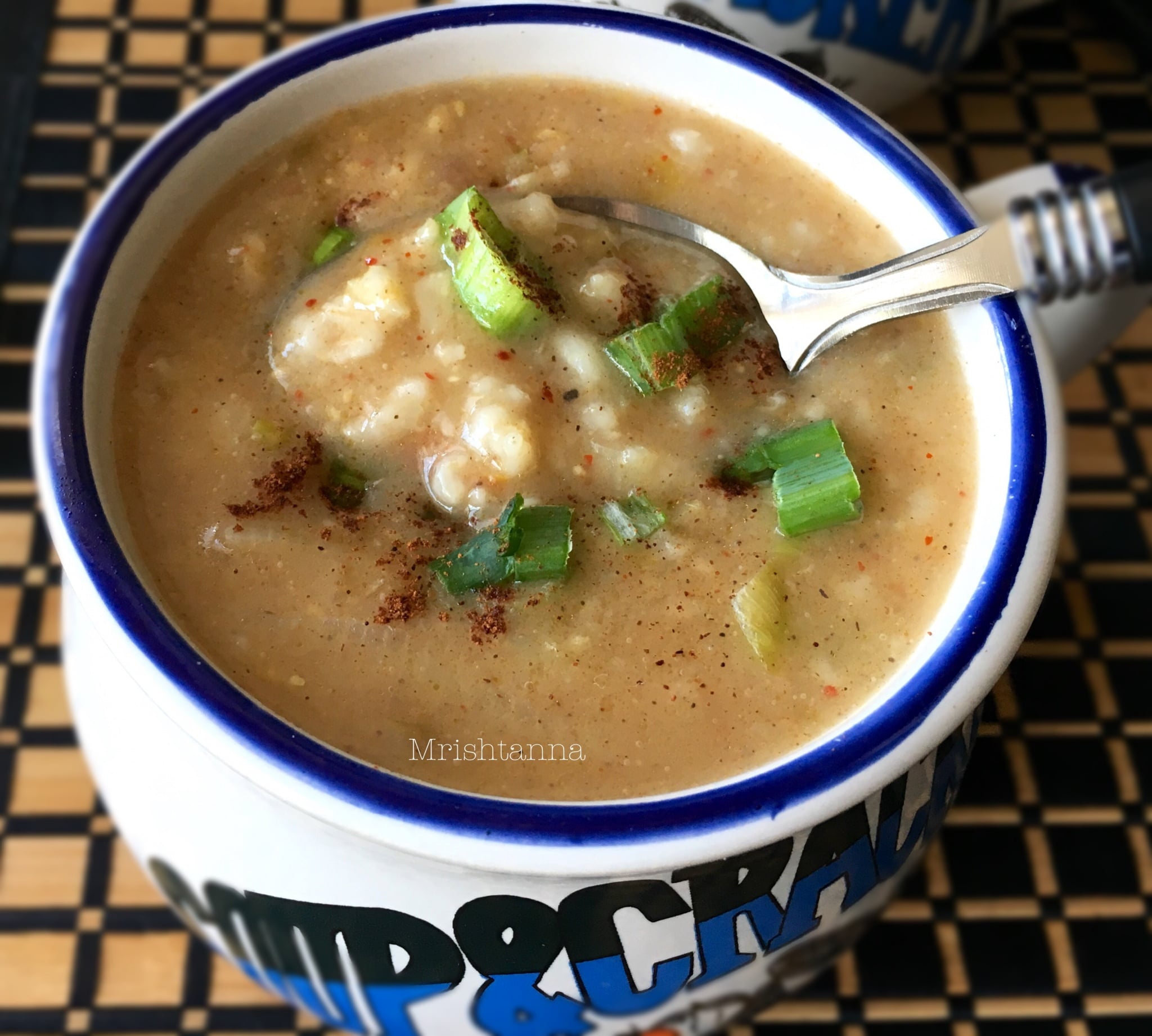 A bowl of soup and a spoon, with oatmeal