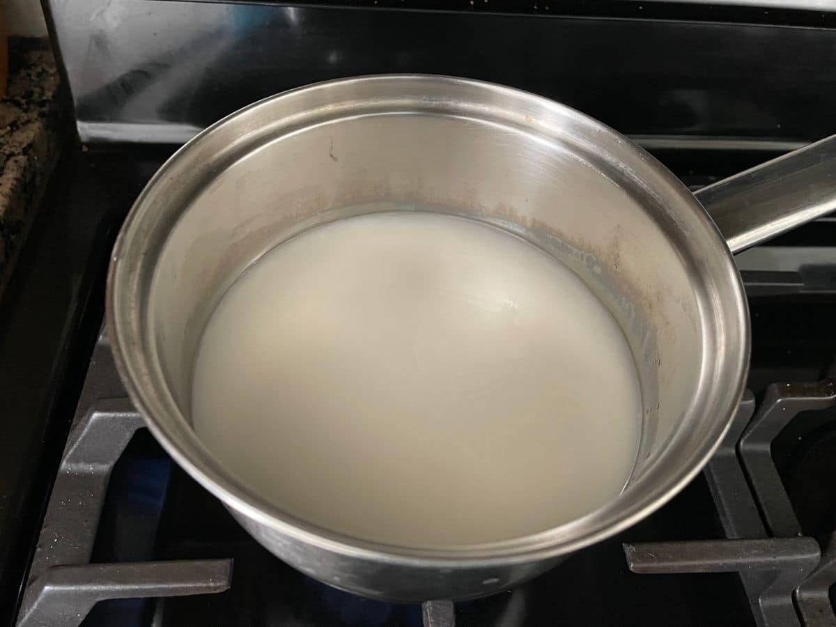 a small saucepan is with oatmilk and water over the stove top.