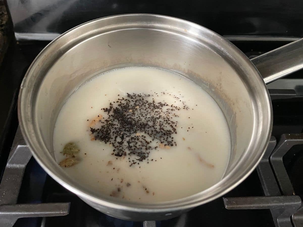 a small pot with oat milk and tea leaves over the heat to make chai.