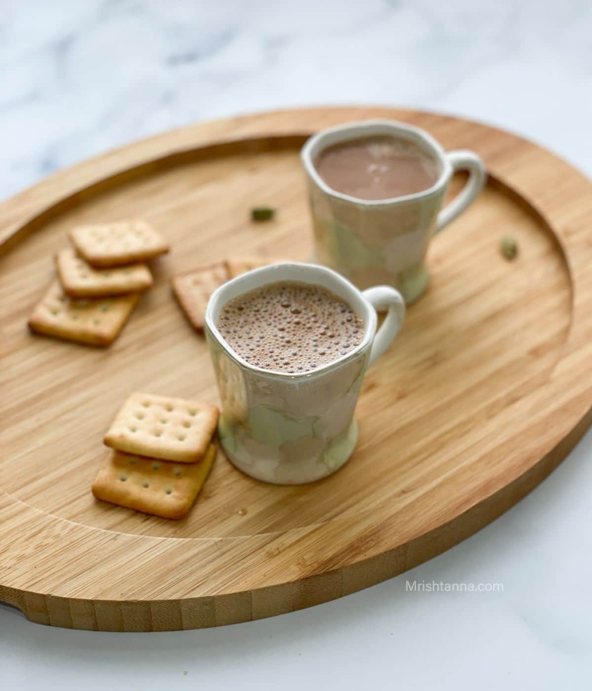 Two cups of vegan masala chai is on the wooden tray.