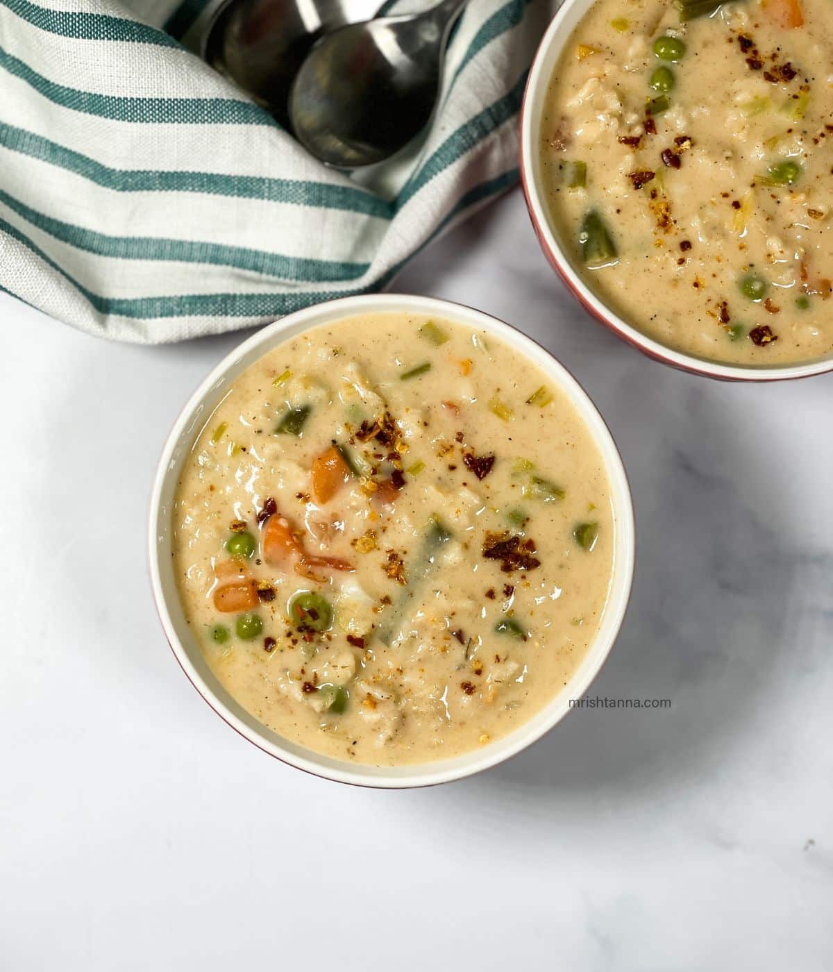 A bowl has oats soup with vegetables.