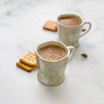 Two cups of vegan chai tea is on the table.