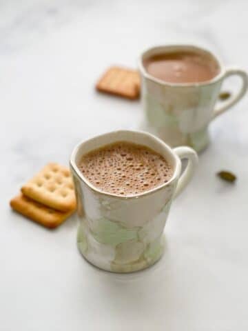 Two cups of vegan chai tea is on the table.