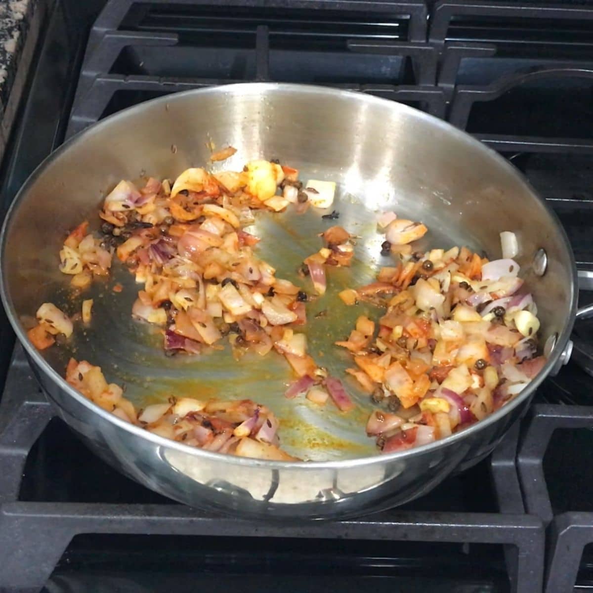 A pan is with onions and spices over the medium heat for spinach soup