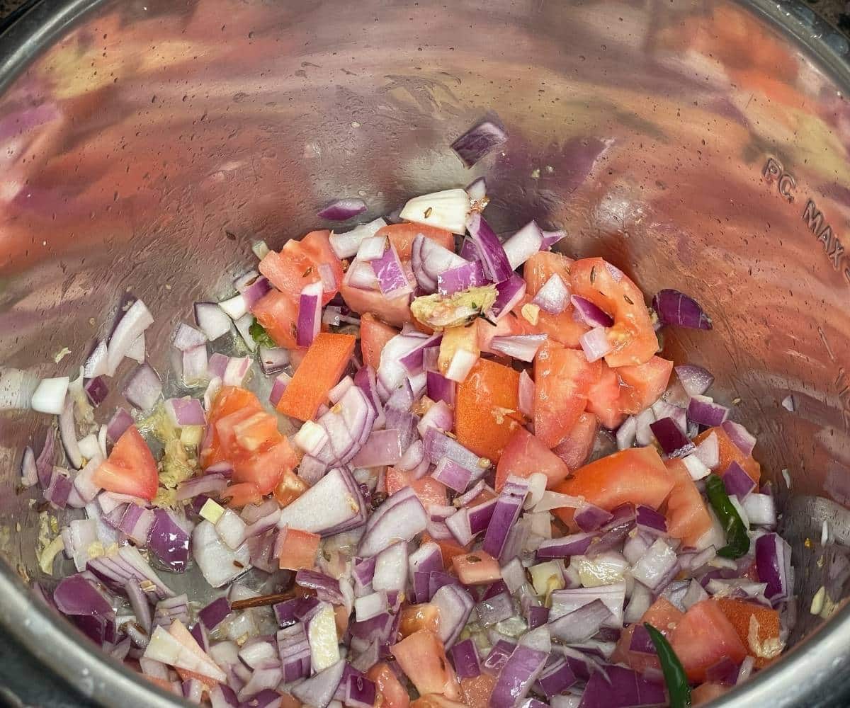 A pot is with onions. tomatoes for aloo palak Curry.