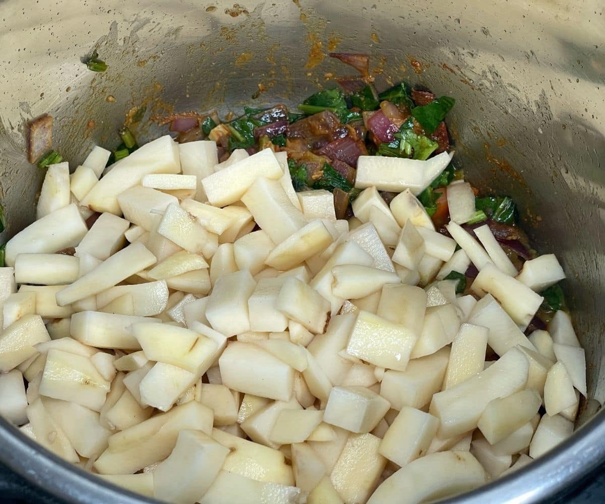 An instant pot is filled with potatoes for aloo palak Curry.